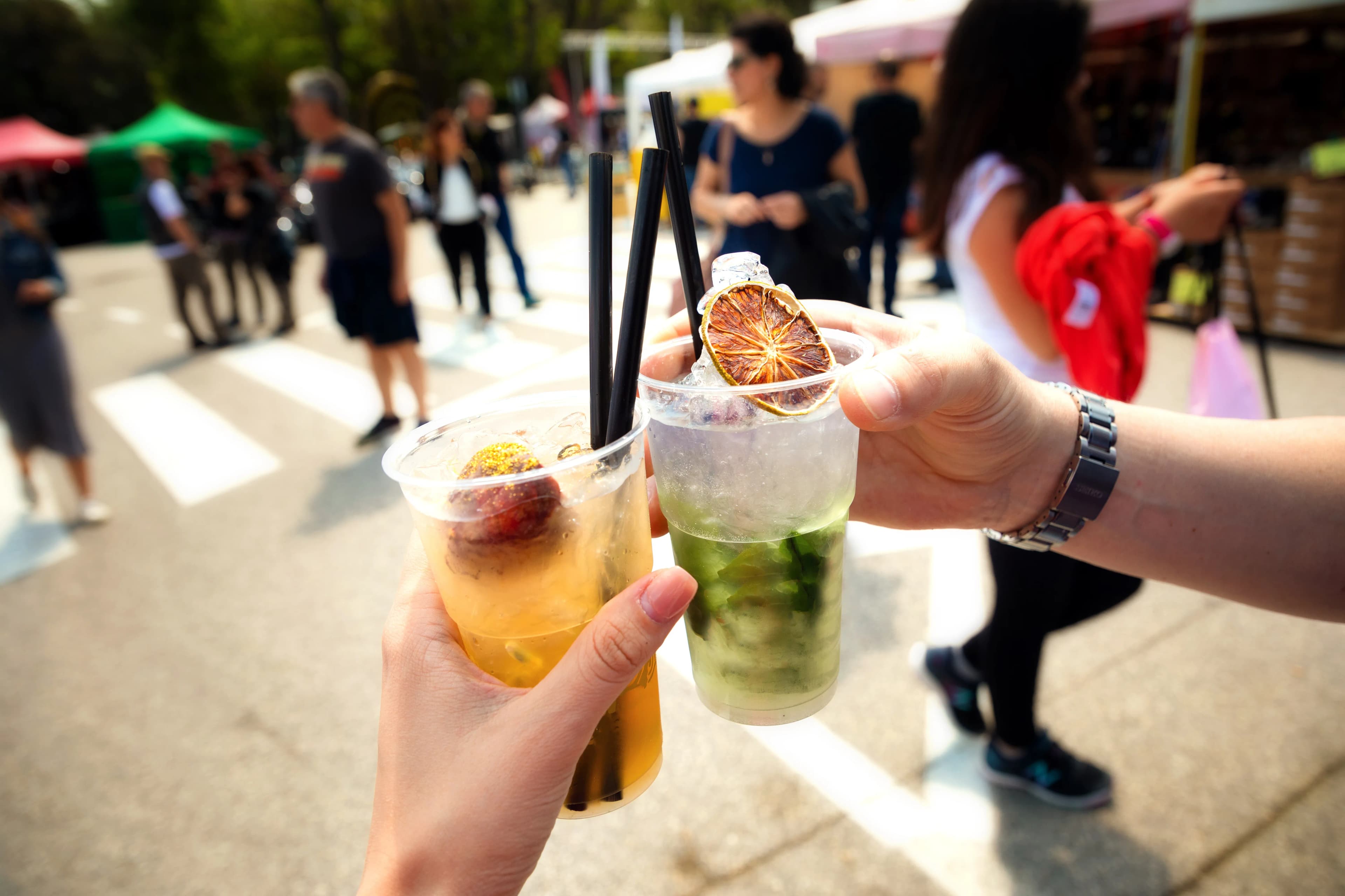 twee mensen die proosten met een cocktail die ze net hebben gehaald bij een cocktailbar op een festival